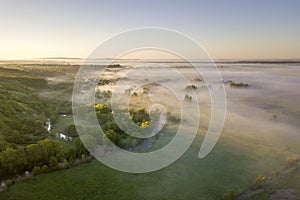 Top view of green cultivated hills and green trees in foggy valley. Spring misty landscape panorama at dawn