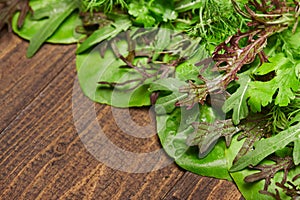 Top view of green dill, parsley, salad, herbs and other greens on a dark wooden background, concept of fresh vegetables and