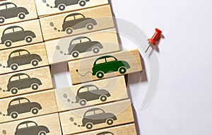 Top view of green electric car between polluting fossil combustion vehicles. Wooden cut