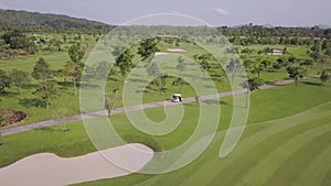 Top view of green golf course, perfect tropical place, golf cart on the road