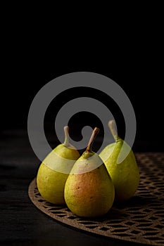 Top view of green pears on trellis and wooden table, selective focus, black background, vertical