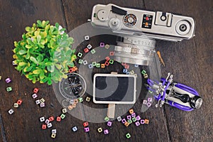 top view green plant, compass, vintage camera and souvenir on wooden floor ideal for travel and vacation concept background