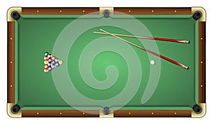 Top view of a green pool table with balls and cues