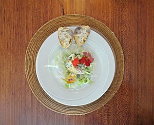 Top view of green salad with comestible flowers and bread