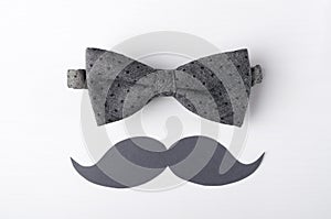 Top view of grey bow tie ad mustache on the white surface.Concept of greeting card, happy fathers day