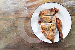 Top view of grilled chicken in white plate on wood background with copy space