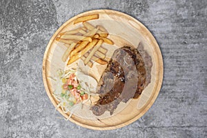 Top view Grilled pork steak with vegetable salad and french fries on wooden table