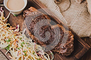 Top view grilled ribeye beef steak with stew cabbage and wineglass of red wine, herbs and spices over brown sackcloth on