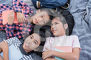 Top view. Group of Asian elementary school children talk while lying on the blanket and relaxation in the summer at park in