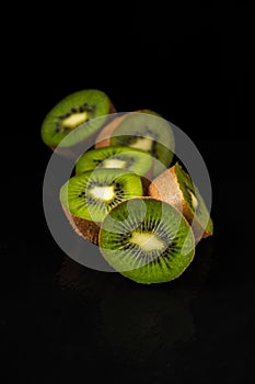 Top view of a group of cut green kiwis, selective focus, black background