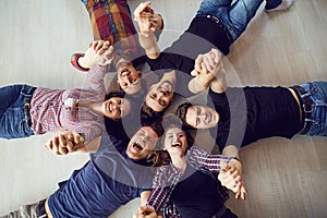 Top view. A group of friends are laughing lying on the floor.