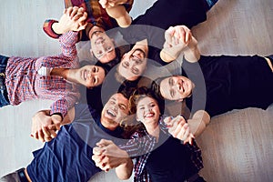 Top view. A group of friends are laughing lying on the floor.