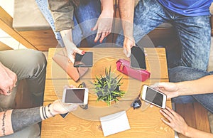 Top view of a group of hipster friends sitting in a bar cafe using mobile smart phone