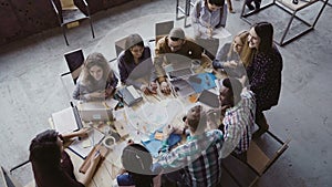 Top view of group of mixed race people sitting at table, talking and then start to clapping together. Business meeting.