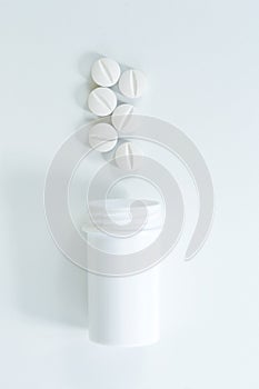 Top view of a group of pills and plastic bottle on white