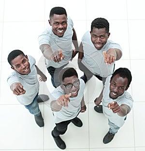 Top view. a group of smiling friends pointing at the camera