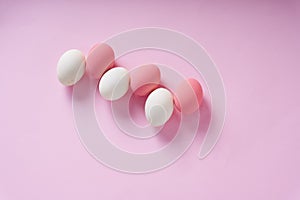 Top view - Group of white and pink eggs over pink background
