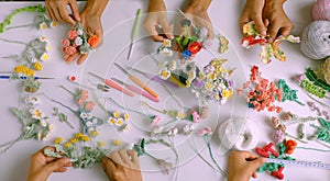 Top view group of woman hand work with yarn to make handmade product, colorful tiny flower crochet as rose, daisy, fern leaf,