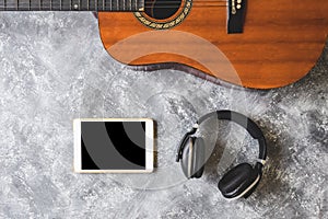 Top view of Guitar with headphone and tablet on grunge background.