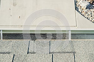 Top view of a gutter system on a residential house.  Asphalt shingles and support brackets visible