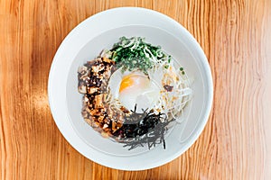 Top view of Hakata style Mazesoba: Dry ramen with Chasiu bits, spring onions, bamboo shoots, chilli oil, leeks, sesame seeds.