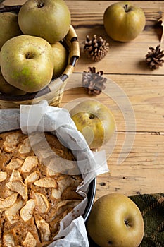 Top view of half apple pie, on wooden table with leaves and pippin apples, selective focus