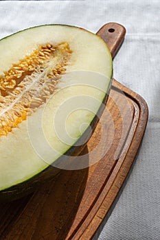 Top view of half green melon with seeds, on wooden table and white tablecloth