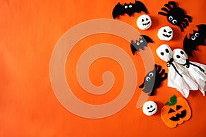 Top view of Halloween crafts, orange pumpkin, ghost and spider on orange background