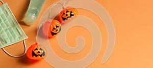 Halloween pumpkin lights, medical mask and alcohol sanitizer gel on orange background. Halloween , COVID-19 prevention and new