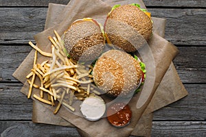 top view of hamburgers, french fries, ketchup and mayonnaise on baking paper