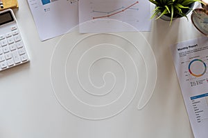 Top view hand of accountant using calculator on workplace with copy space, calculator and plant potted on white desk