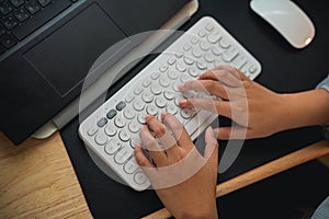 Top view. Hand of businesswoman typing on keyboard and working laptop on wooden table at home. Entrepreneur woman working for her