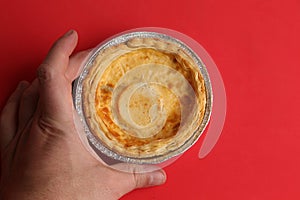 Top view of a hand golding meat pie isolated on a red background