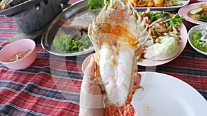 Top view of hand holding barbecued shrimp in restaurant