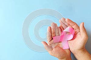 Top view of hand holding color pink awareness ribbon. Women`s health and breast cancer awareness care and prevention concept.