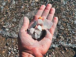 top view of a hand holding colorful pebbles at beach - Bodrum, Turkey