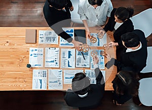 Top view hand holding gear by group of businesspeople on table in harmony office