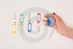 top view of hand holding key beside set of keys with colorful labels
