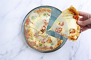 Top view of hand taking a slice of pizza