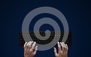 Top view, Hand typing computer keyboard on blue background