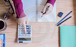 Top view. Hand woman using finances and calculator on table at home office.