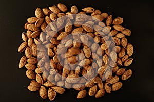 Top view of handful of pecans, almonds on a black background.