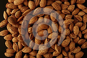 Top view of handful of pecans, almonds on a black background. Closeup. Micro.