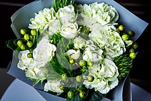 Top view on handmade elegant bouquet of big white roses and fresh greenery