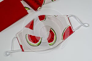 Top view on handmade fabric cotton reversible face mask in white and red with watermeloon pattern. Protection against saliva,