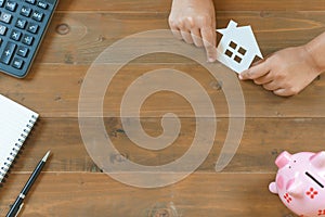 Top view of hands holding house paper with calculator, notebook