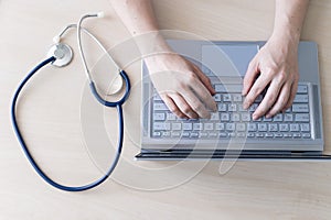 Top view of hands on the keyboard. Woman doctor at the desk typing on a laptop. A nurse fills out a patient electronic