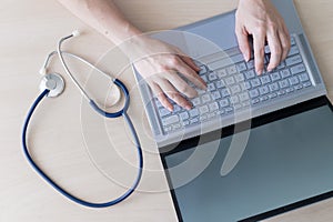 Top view of hands on the keyboard. Woman doctor at the desk typing on a laptop. A nurse fills out a patient electronic