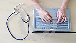 Top view of hands on the keyboard. Woman doctor at the desk typing on a laptop. A nurse fills out a patients electronic