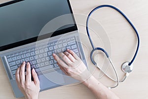 Top view of hands on the keyboard. Woman doctor at the desk typing on a laptop. A nurse fills out a patients electronic